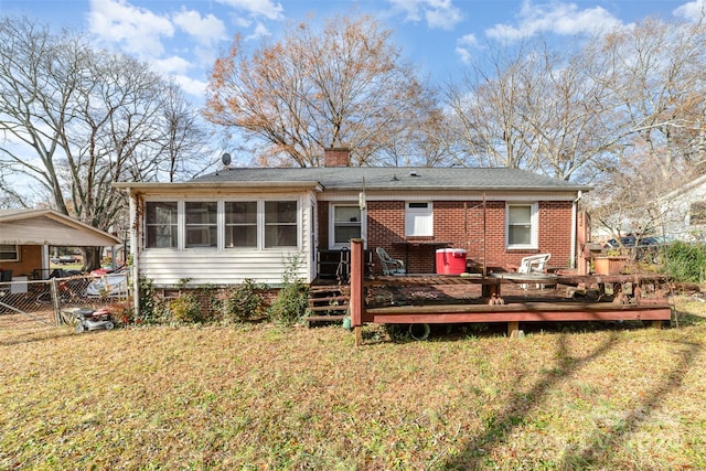 rear view of house featuring a yard, a deck, and a sunroom