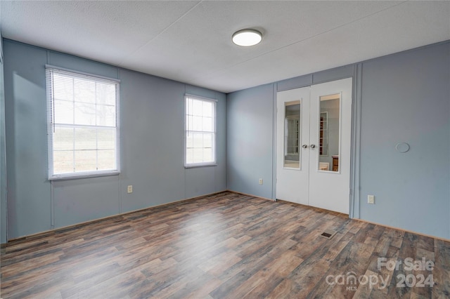 empty room featuring a textured ceiling, dark wood-type flooring, and french doors