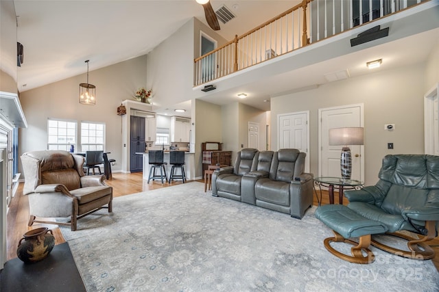 living room featuring an inviting chandelier, light hardwood / wood-style floors, and high vaulted ceiling