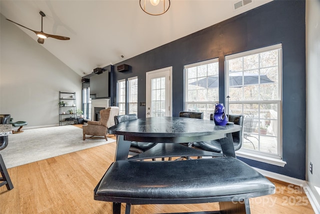 dining room with ceiling fan, wood-type flooring, and high vaulted ceiling