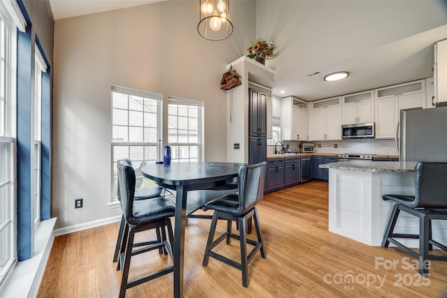 kitchen featuring blue cabinetry, white cabinetry, a high ceiling, decorative backsplash, and appliances with stainless steel finishes