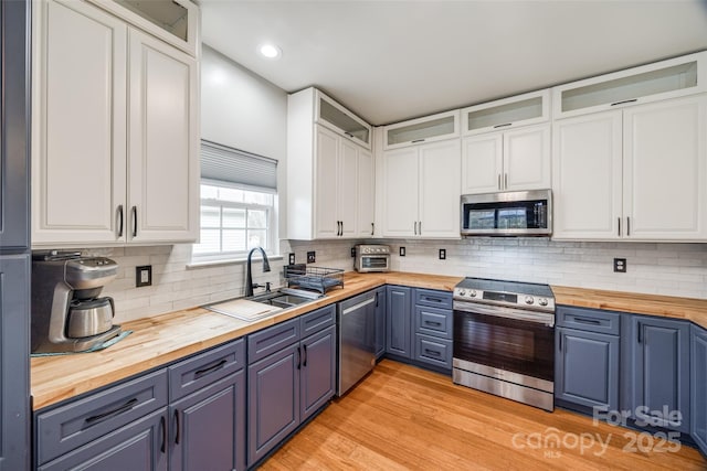 kitchen featuring wood counters, stainless steel appliances, white cabinetry, and sink