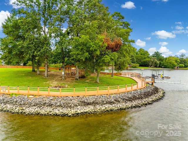 view of community with a yard, a water view, and a dock