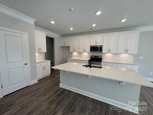 kitchen featuring white cabinets, sink, stainless steel appliances, and an island with sink