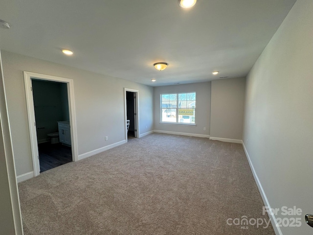 unfurnished bedroom featuring connected bathroom and dark carpet