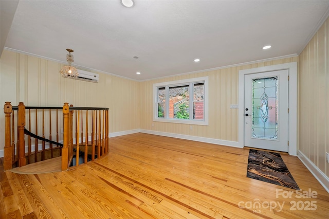 entrance foyer with hardwood / wood-style floors, a wall mounted air conditioner, and ornamental molding