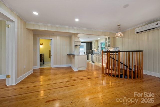 interior space with ornamental molding, light hardwood / wood-style floors, sink, and an AC wall unit