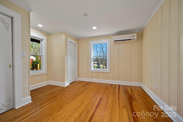 interior space featuring light hardwood / wood-style flooring, ornamental molding, a wealth of natural light, and a wall unit AC