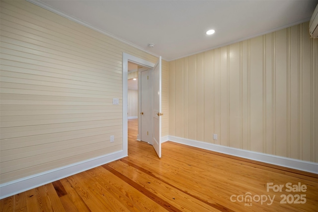 spare room featuring crown molding, a wall unit AC, and light hardwood / wood-style flooring