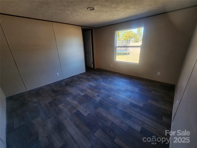 unfurnished bedroom with dark hardwood / wood-style floors and a textured ceiling