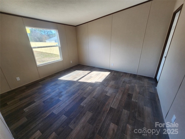 empty room featuring dark hardwood / wood-style flooring and a textured ceiling