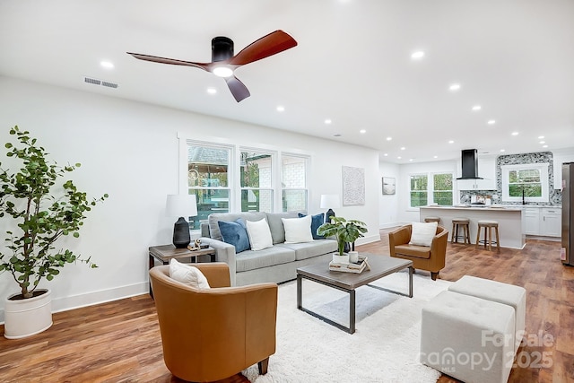 living room featuring sink, light wood-type flooring, plenty of natural light, and ceiling fan