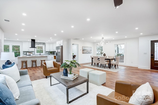 living room featuring plenty of natural light, sink, and light hardwood / wood-style flooring