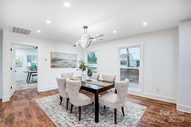 dining area with ceiling fan with notable chandelier, a healthy amount of sunlight, and dark hardwood / wood-style floors