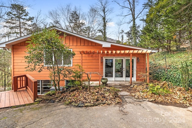 rear view of property featuring a wooden deck and french doors