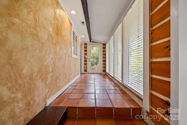 hallway with tile patterned floors and vaulted ceiling