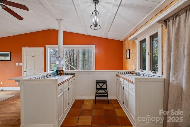 kitchen with hanging light fixtures, lofted ceiling, a wealth of natural light, and kitchen peninsula