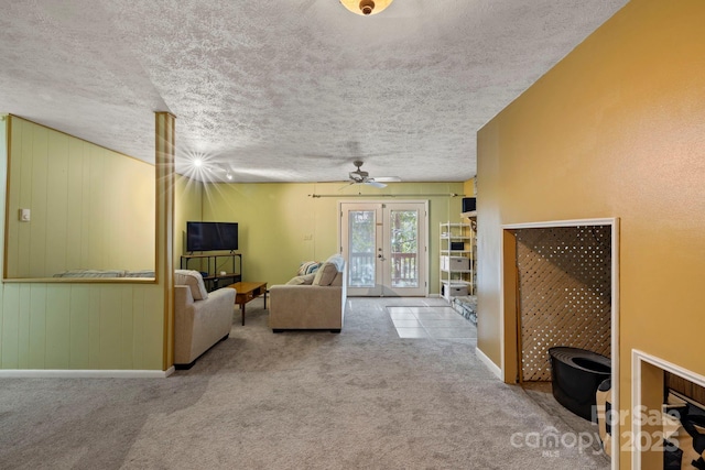 carpeted living room with wood walls, a textured ceiling, and french doors