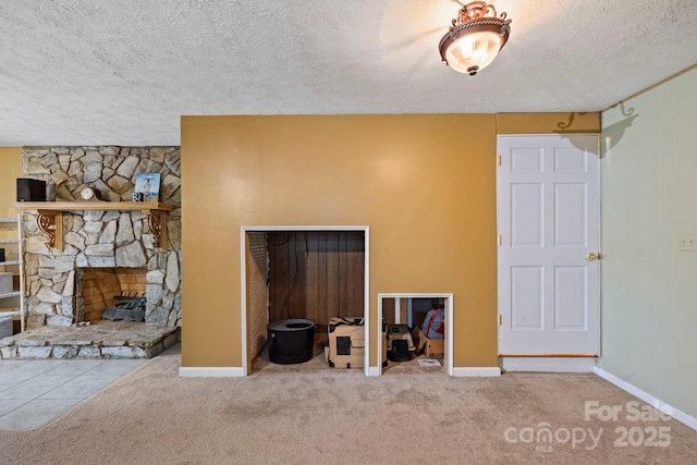 unfurnished living room with a stone fireplace, carpet floors, and a textured ceiling