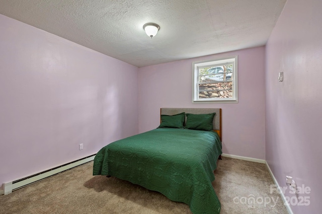 carpeted bedroom featuring a baseboard heating unit and a textured ceiling