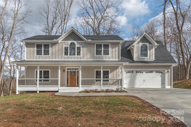 view of front of property featuring a porch, a garage, and a front lawn