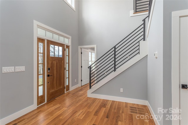 entryway with light hardwood / wood-style flooring and a towering ceiling