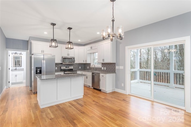 kitchen featuring white cabinetry, a kitchen island, stainless steel appliances, and decorative light fixtures