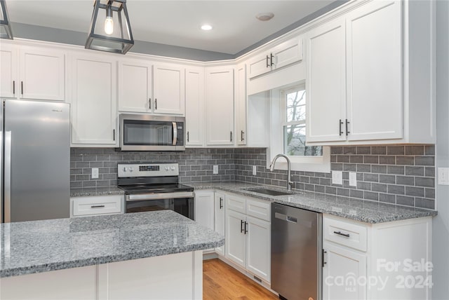 kitchen with white cabinets, stainless steel appliances, light stone countertops, and sink