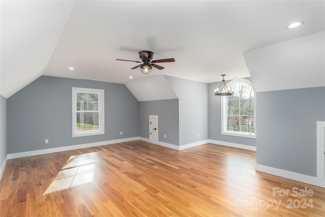 bonus room with ceiling fan with notable chandelier, lofted ceiling, and light hardwood / wood-style flooring