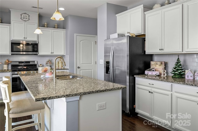 kitchen with appliances with stainless steel finishes, sink, a center island with sink, and backsplash