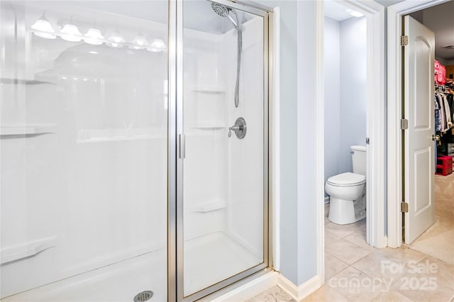 bathroom with tile patterned floors, toilet, and a shower with shower door