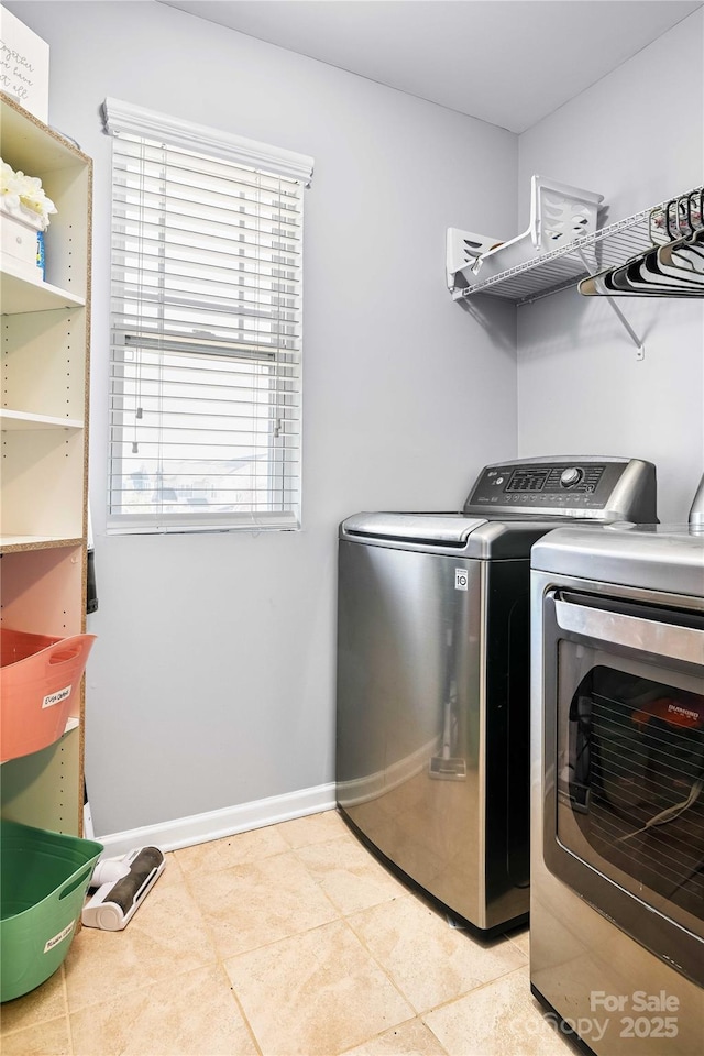 washroom with light tile patterned floors, washer and clothes dryer, and plenty of natural light