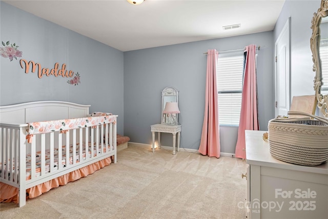 bedroom featuring light colored carpet and a nursery area