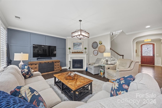 living room with wood-type flooring, ornamental molding, and a chandelier