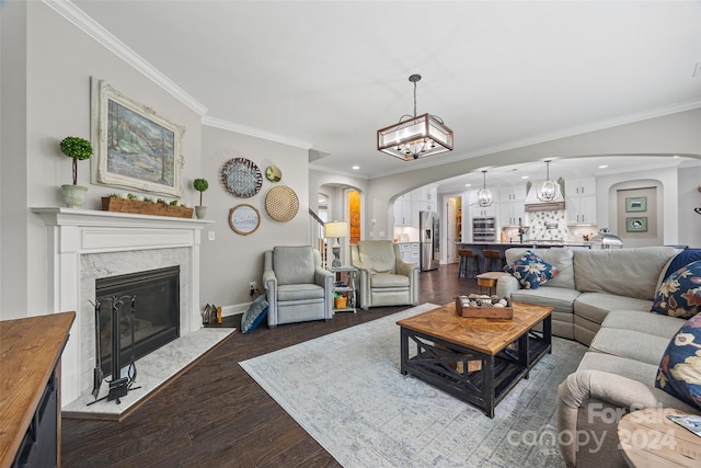 living room with dark hardwood / wood-style flooring, a premium fireplace, ornamental molding, and a chandelier