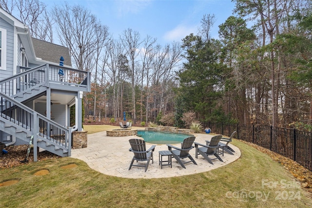 view of pool with a lawn, a fire pit, and a patio