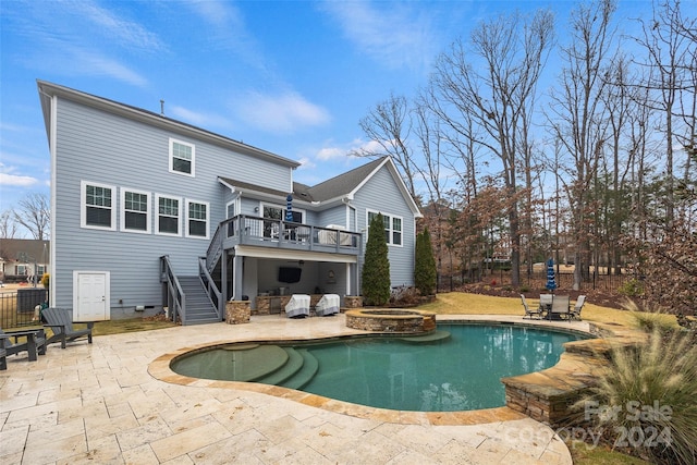 back of house featuring a swimming pool with hot tub, a balcony, and a patio