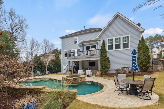 back of property with a patio area, a balcony, and a pool with hot tub