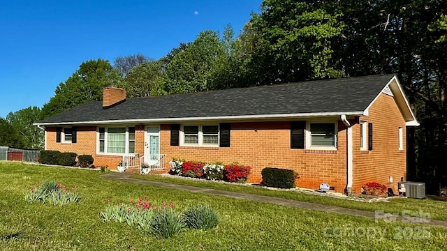 ranch-style home featuring central air condition unit, brick siding, a chimney, and a front yard