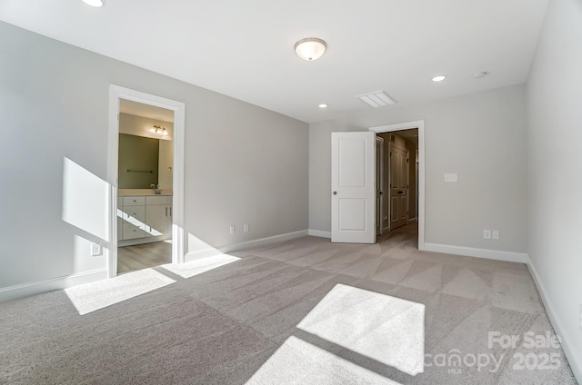 unfurnished bedroom with ensuite bath and light colored carpet