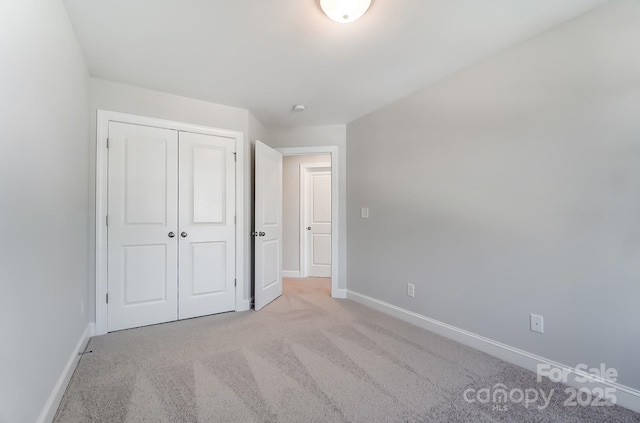 unfurnished bedroom featuring a closet and light colored carpet