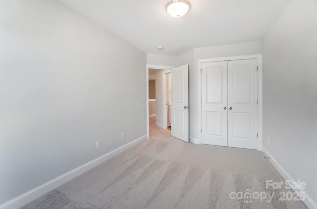 unfurnished bedroom featuring light carpet and a closet