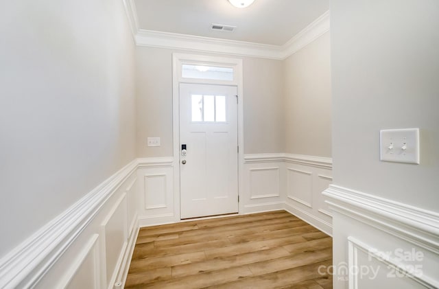 entryway with light hardwood / wood-style flooring and crown molding