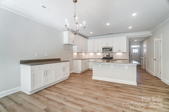 kitchen featuring decorative light fixtures, sink, white cabinetry, and ornamental molding