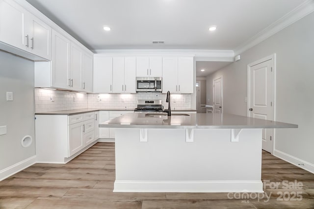 kitchen with white cabinets, appliances with stainless steel finishes, sink, and a center island with sink