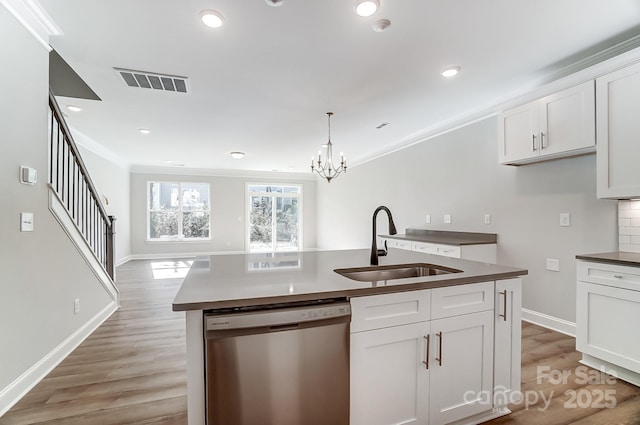 kitchen with a center island with sink, dishwasher, ornamental molding, white cabinets, and sink