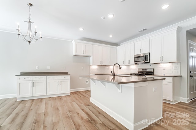 kitchen featuring white cabinets, a kitchen island with sink, sink, and stainless steel appliances