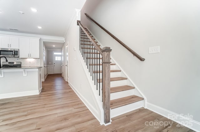 stairway featuring wood-type flooring and crown molding