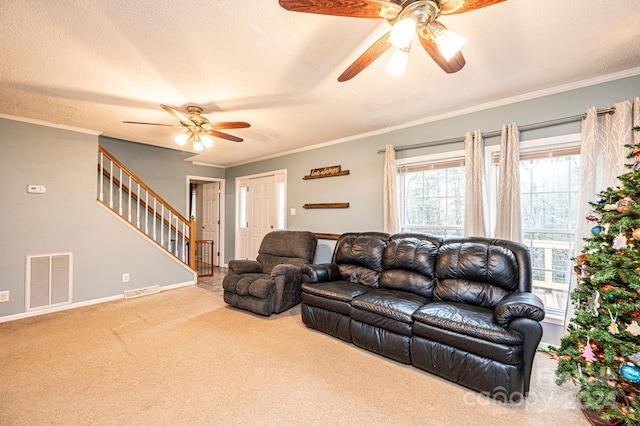 living room with carpet flooring, ceiling fan, ornamental molding, and a textured ceiling