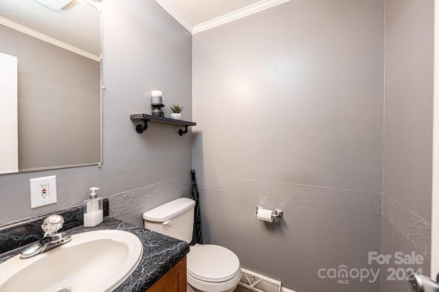 bathroom featuring a textured ceiling, vanity, toilet, and crown molding